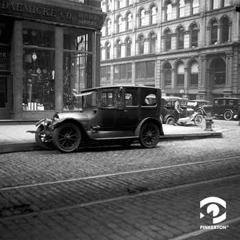 Black and white photo of early 20th century automobile parked on a city street.