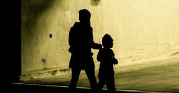 an adult and child are in silhouette as they walk under an overpass