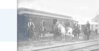 Photograph of men on horses near train tracks